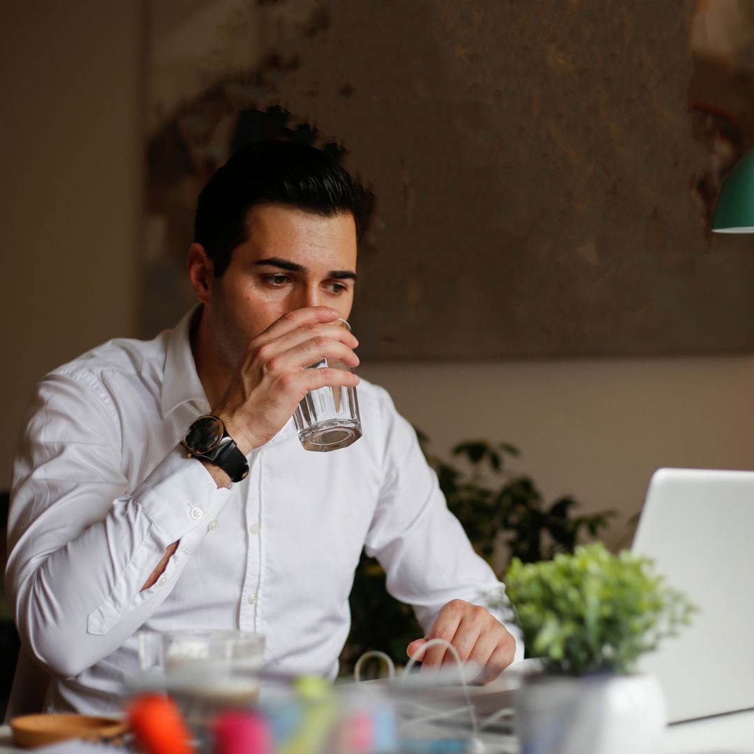 Illustration showing a person drinking water at their desk, symbolizing the importance of hydration at work.